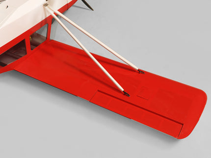 Close-up of a red and white Phoenix Model DECATHLON model airplane wing on a gray background