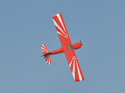 Red and white Phoenix Model DECATHLON airplane flying against a clear blue sky