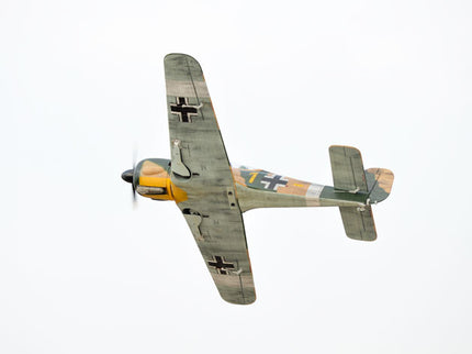 Phoenix Model Focke Wulf 55" with Electric Retracts Vintage airplane with a camouflage pattern and a black cross on the wing, flying against a white background.
