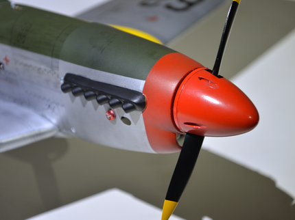 Phoenix Model P51 MUSTANG 1,41m 55,5'' W/Electric Retract Close-up of a model airplane with a red nose and green body on a neutral background