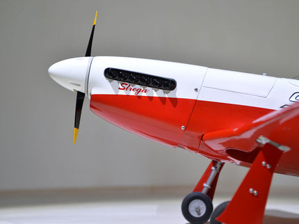Phoenix Model STREGA 56'' W/Electric Retract Red and white model airplane with a propeller on a plain background