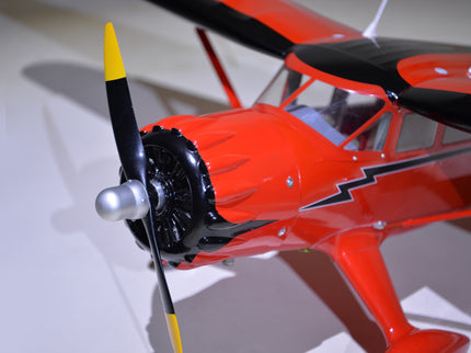 Close-up of a red Phoenix Model STINSON RELIANT 68" ARF model airplane with a black propeller on a white background