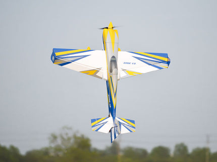 Colorful Phoenix Model EDGE 540 V3 67'' ARF V2 (20-26cc) model airplane flying against a gray sky with trees in the background