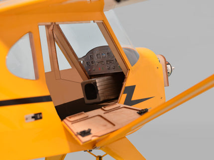 Close-up of a yellow Phoenix Model PIPER J3 CUB model airplane with open cockpit on a gray background