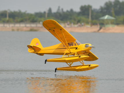 Yellow Phoenix Model PIPER J3 CUB  seaplane on water with a blurred background