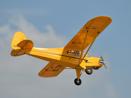 Yellow Phoenix Model PIPER J3 CUB flying against a clear blue sky