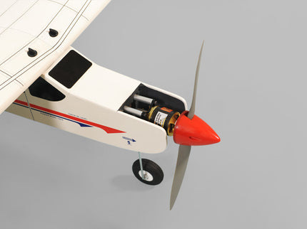 Phoenix Model Domino 62” Trainer Model airplane with a red spinner and  propeller on a gray background