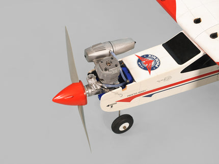 Phoenix Model Domino 62” Trainer Model airplane with red spinner on a gray background